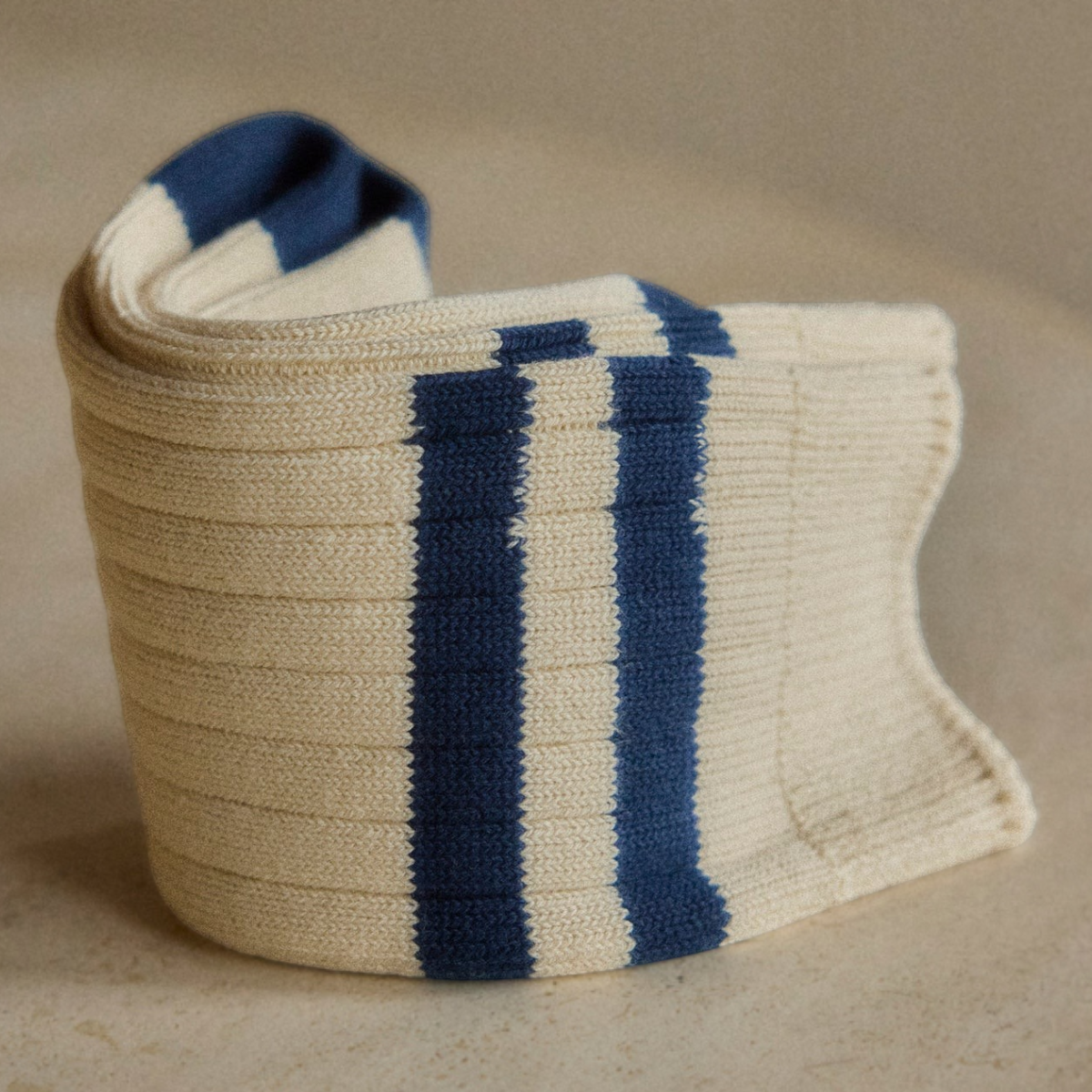 MILWORKS The Racquet Club Collection ribbed cotton socks in cream with navy blue stripes on a stone surface.