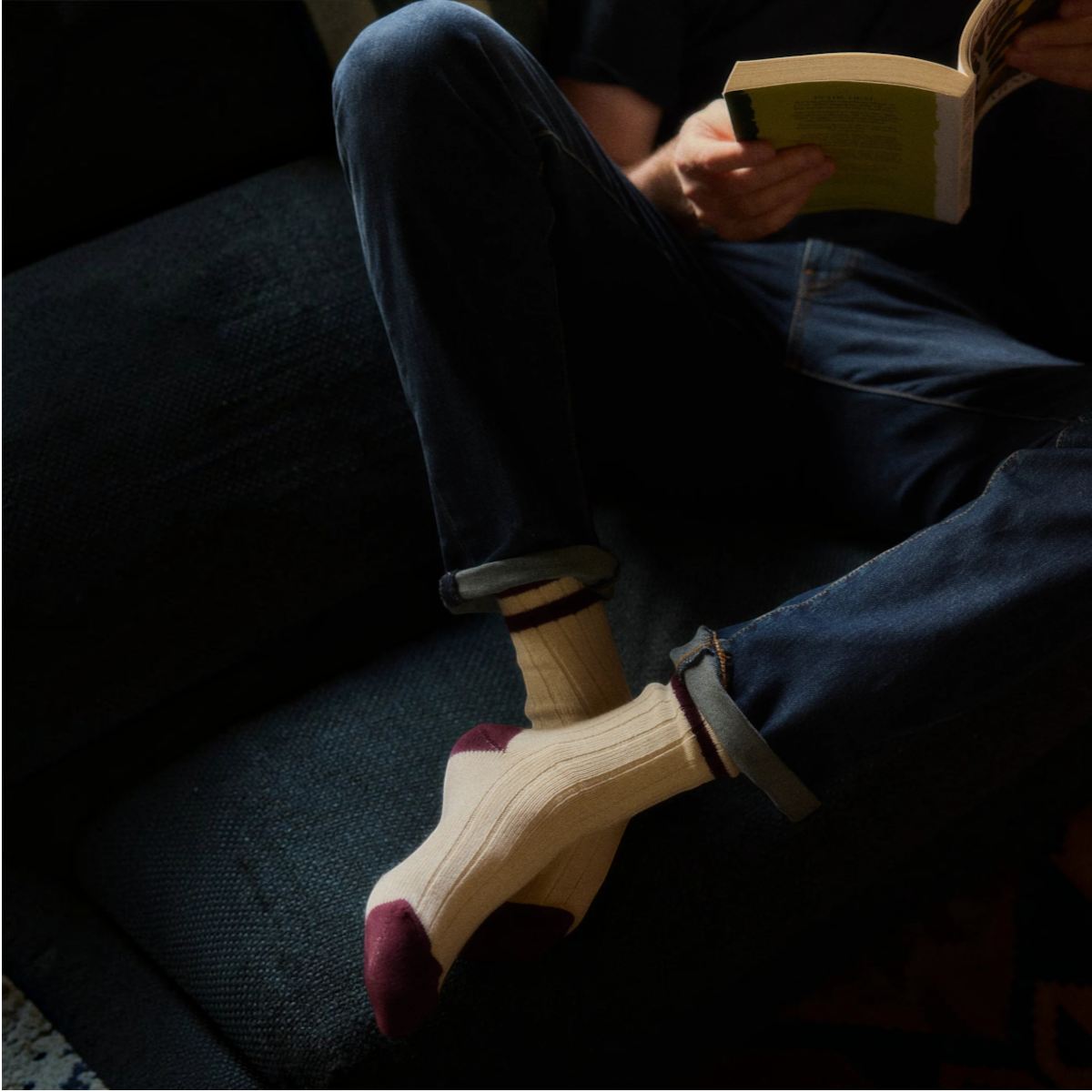 MILWORKS burgundy and cream ribbed cotton athletic socks worn by a person reading a book on a dark sofa