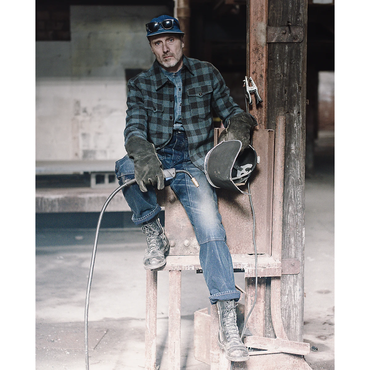 RRL man wearing an indigo denim workshirt with herringbone pattern, band collar, and distressed metal buttons.