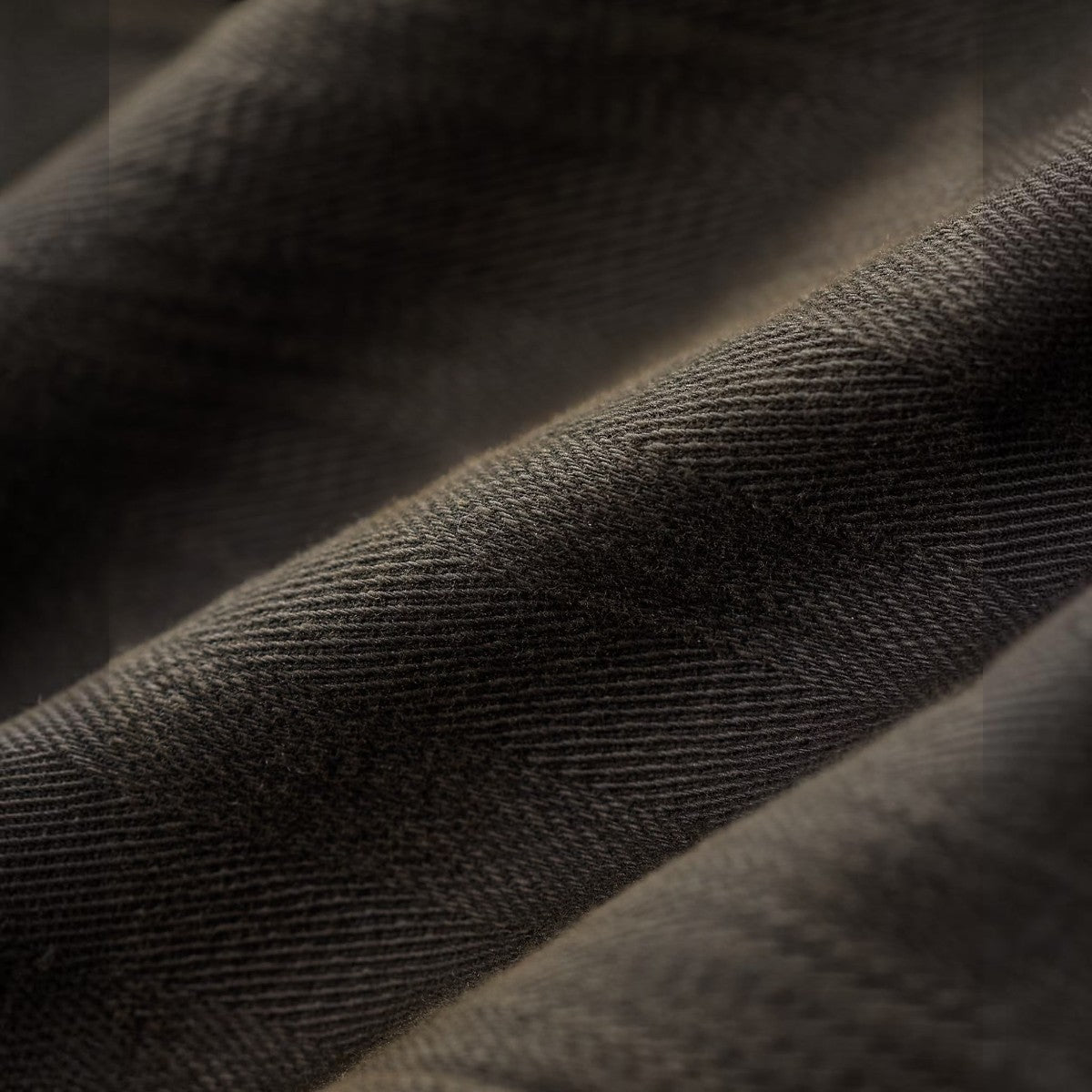 Close-up of RRL washed black jacquard-knit cotton herringbone twill fabric with a textured weave pattern.