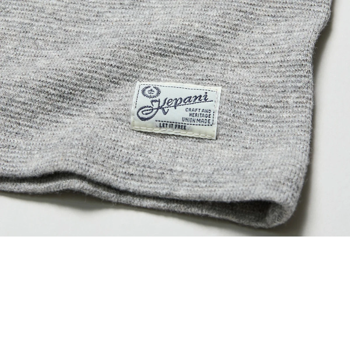 MILWORK Raffy Span Rib Knit Tee in light grey cotton blend with a textured finish and a woven brand label.