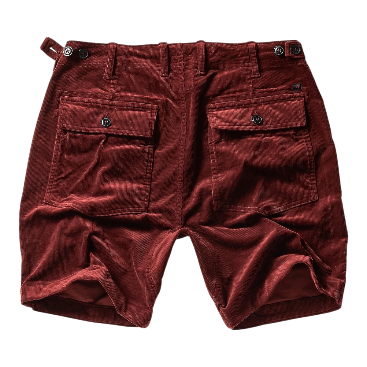 MILWORK Russet corduroy shorts with 7.5" inseam, featuring dual button-flap back pockets and adjustable waist tabs.