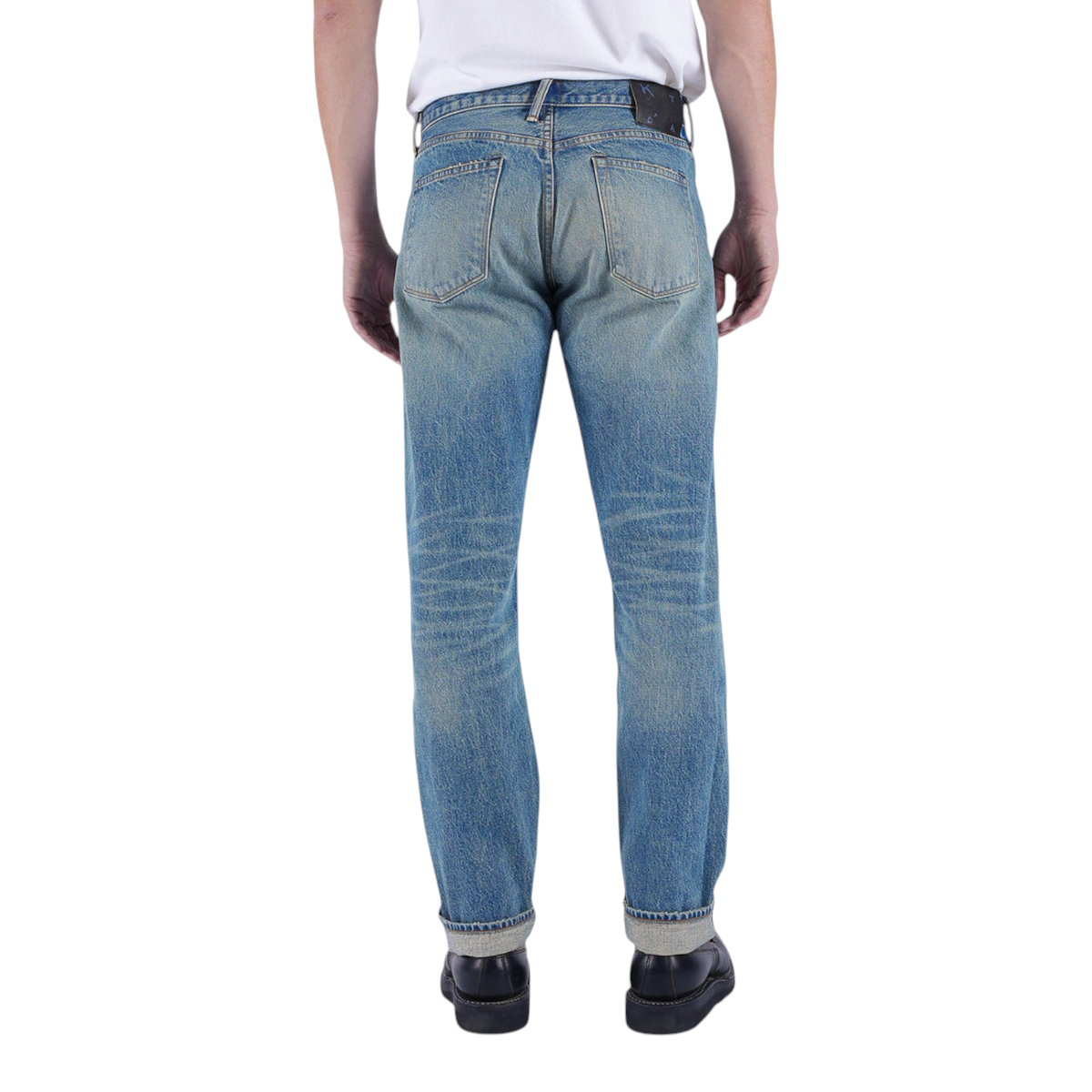 MILWORKS Barrel Classic Straight selvedge jeans in faded indigo with a leather patch, back view on a model.
