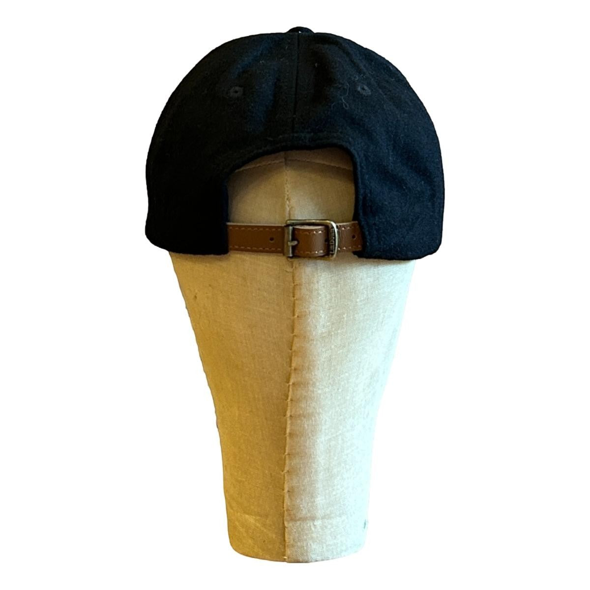 MILWORKS black wool fieldhouse cap with adjustable leather strap and metal clasp, featuring a felt "M" detail.