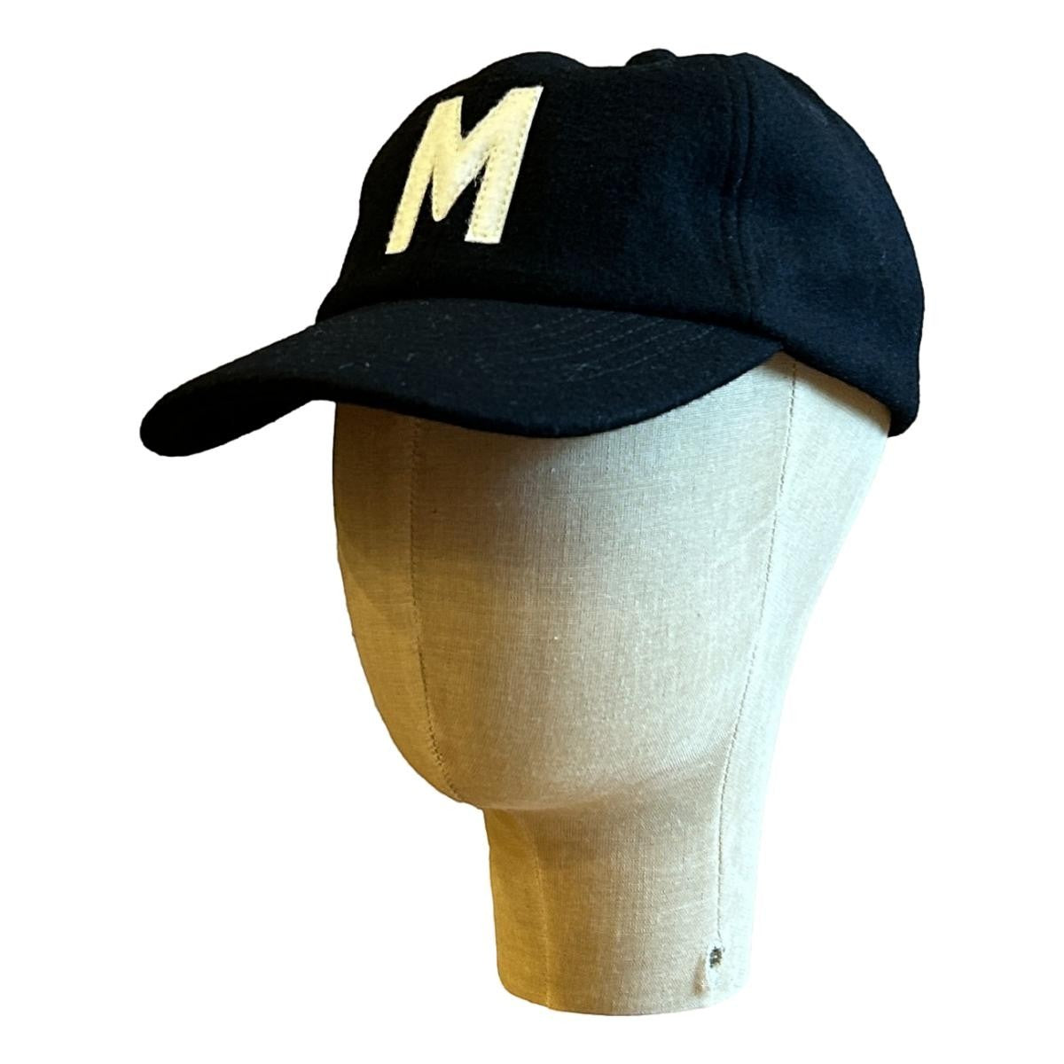 MILWORKS black wool fieldhouse cap with a cream felt "M" logo and flat peak.