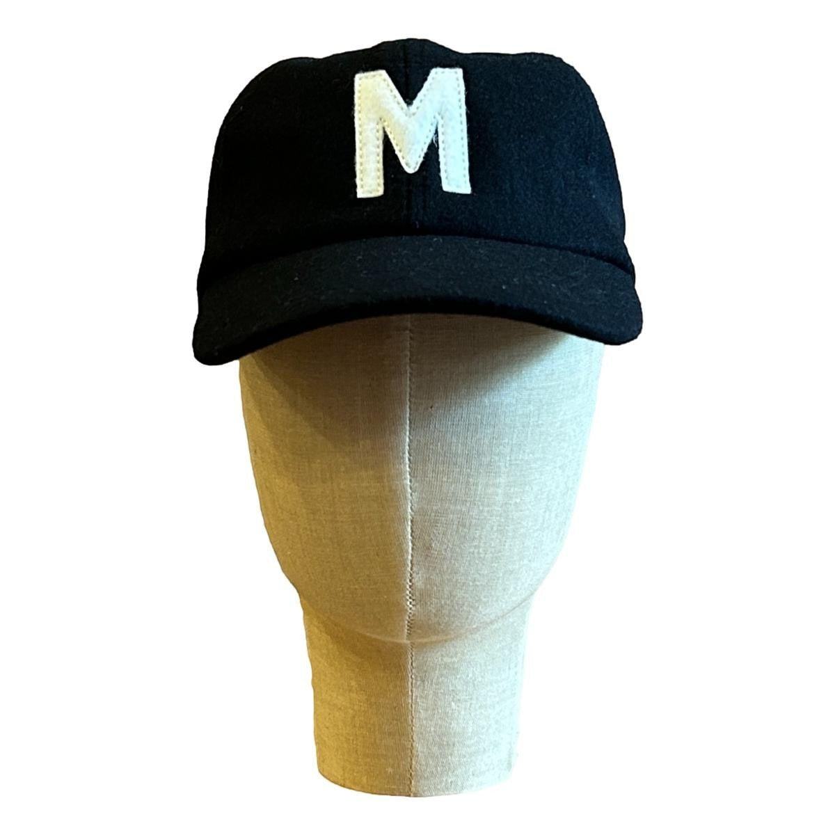 MILWORKS black wool fieldhouse cap with a white felt "M" logo. Unstructured, flat peak, adjustable strap.