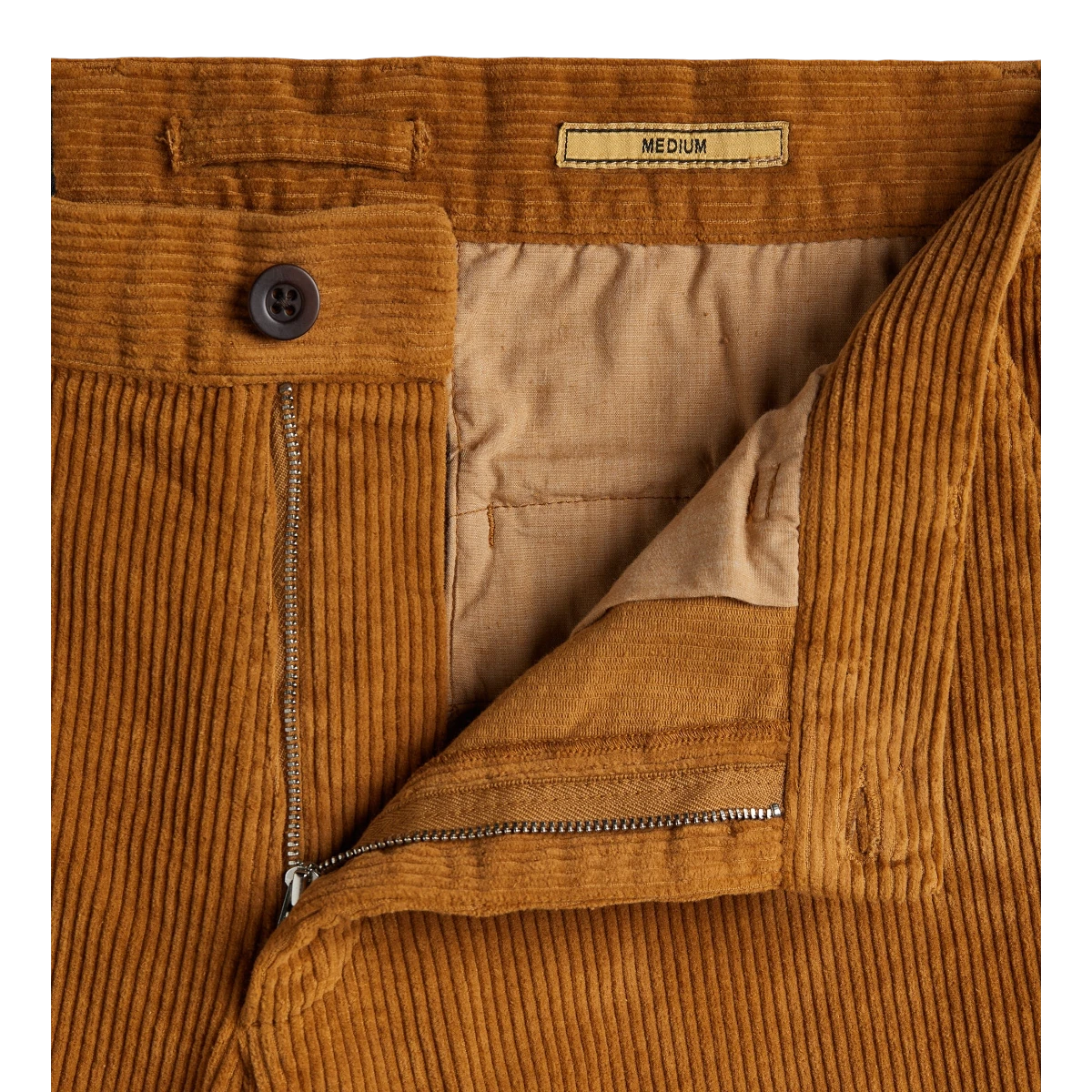 milworks.momrduroy trousers in a warm autumn brown featuring a single pleat, metal zipper, and recycled button detail.