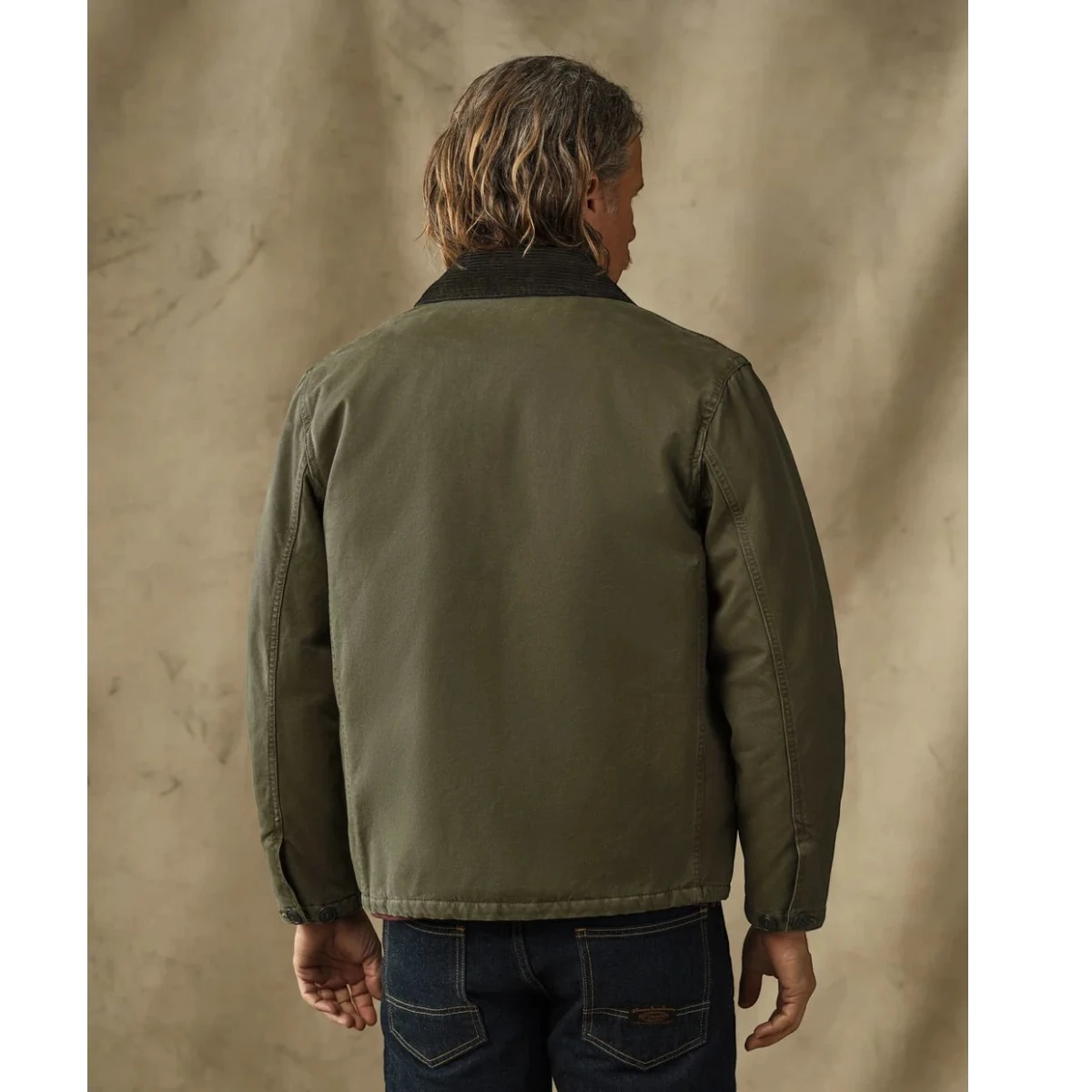 Back view of a man wearing a MILWORKS dark olive insulated canvas outfitter jacket with a corduroy collar
