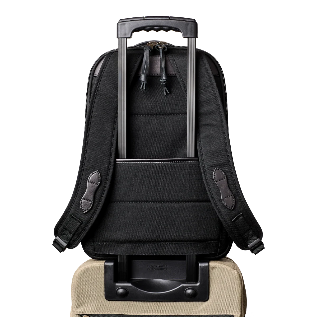 MILWORKS Filson Dryden black Cordura nylon backpack attached to rolling luggage handle, showing rear trolley strap.