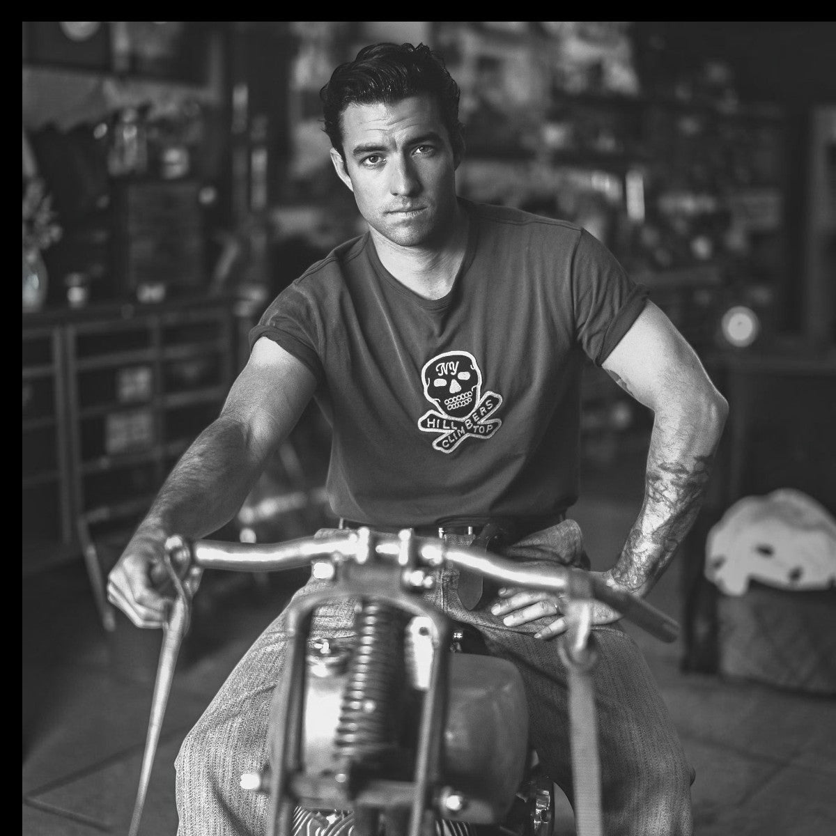 MILWORKS faded black cotton jersey t-shirt with a vintage skull patch, worn by a man on a motorcycle.