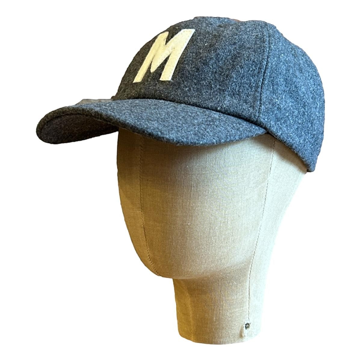 MILWORKS grey wool fieldhouse cap with a cream felt "M" applique and flat peak, adjustable strap with metal clasp.