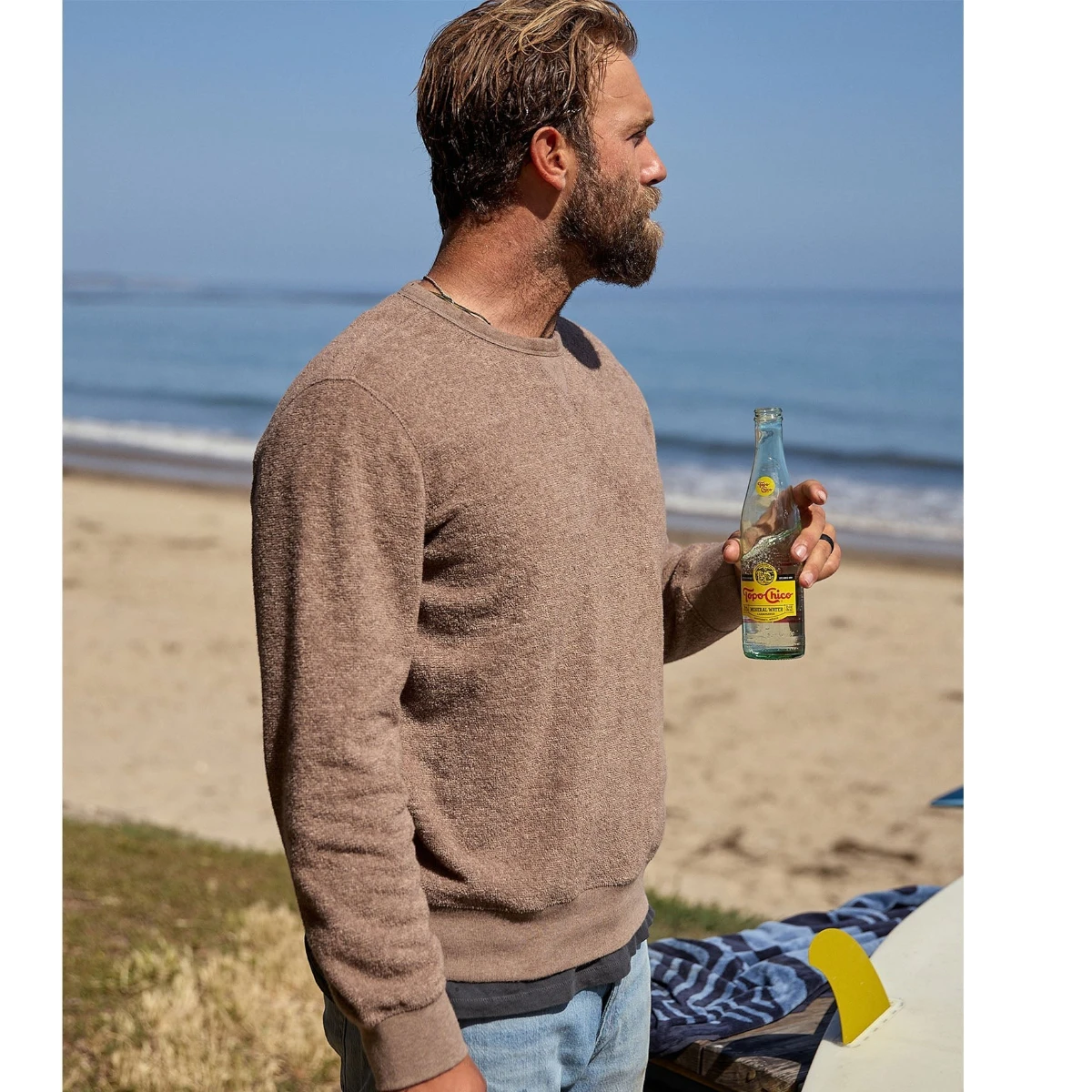 MILWORKS Hightide Crew sweatshirt in heather coconut brown, a casual crew neck with a textured knit, worn by a man on a beach.