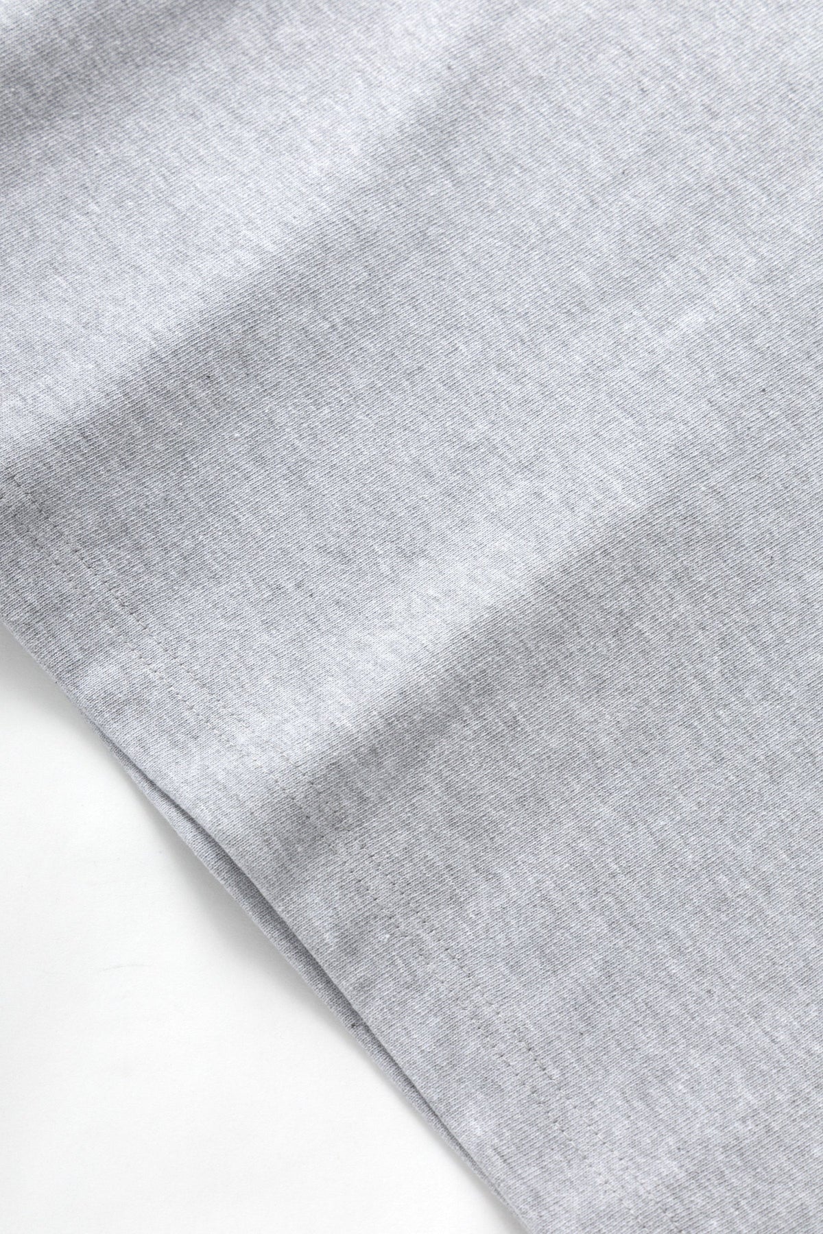 Close-up of MILWORKS 10oz heavyweight heather grey organic cotton jersey fabric with a dense, durable texture.