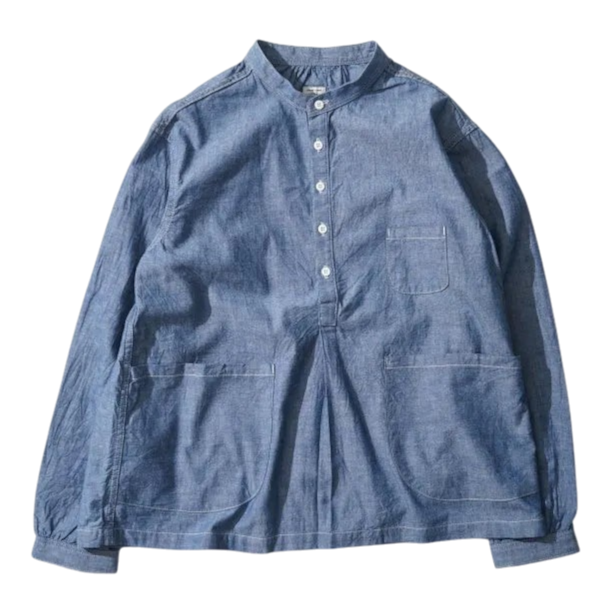 MILWORKS indigo chambray pullover work shirt with a boxy fit, mandarin collar, and oversized front pockets.