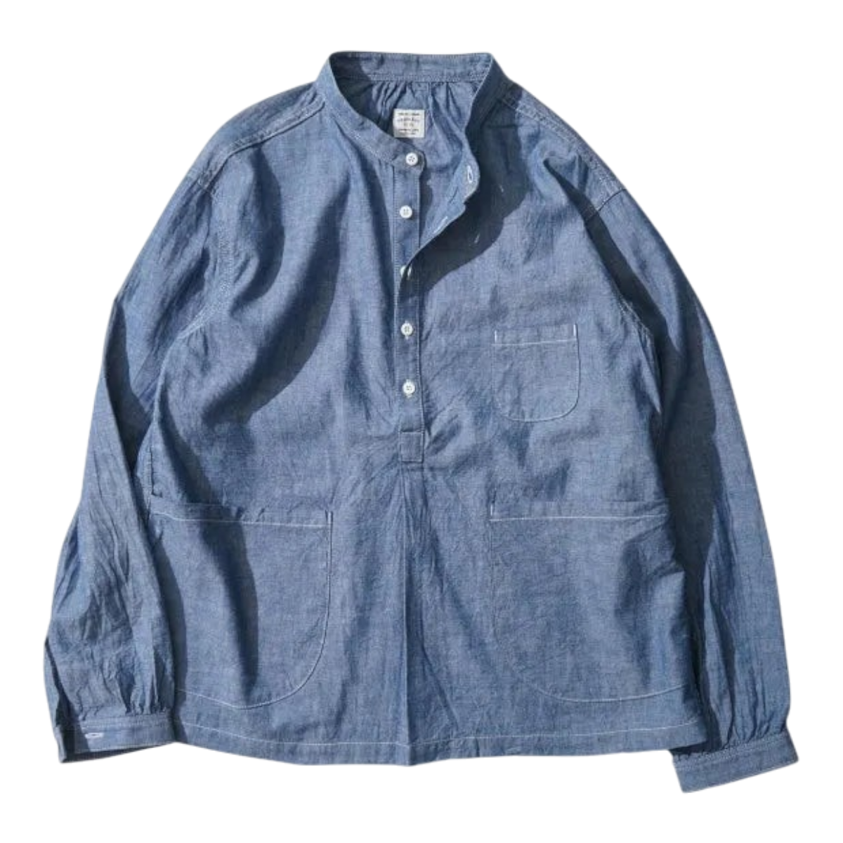 MILWORKS indigo chambray pullover work shirt with a boxy fit, mandarin collar, and oversized front pockets.