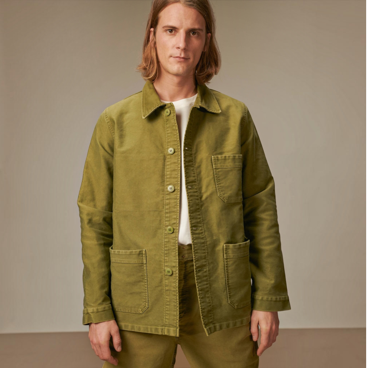 MILWORKS vintage washed khaki moleskin work jacket worn by a man with long hair against a neutral studio background.
