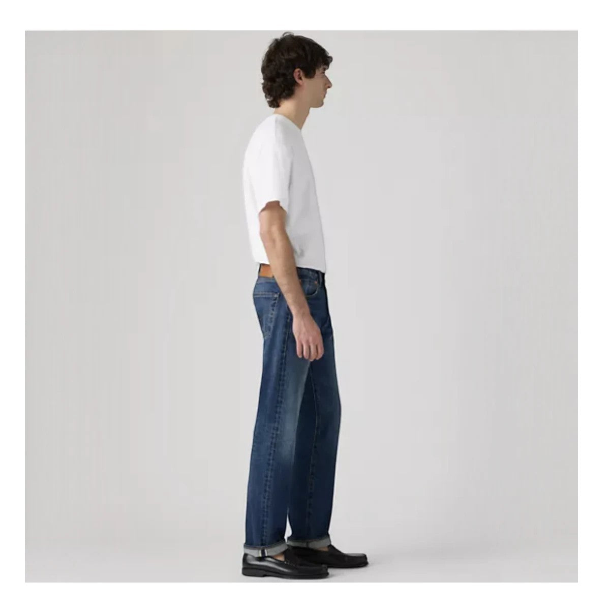 MILWORKS model wearing Levi's 501 Original selvedge jeans in a medium wash with a straight leg fit, side view.