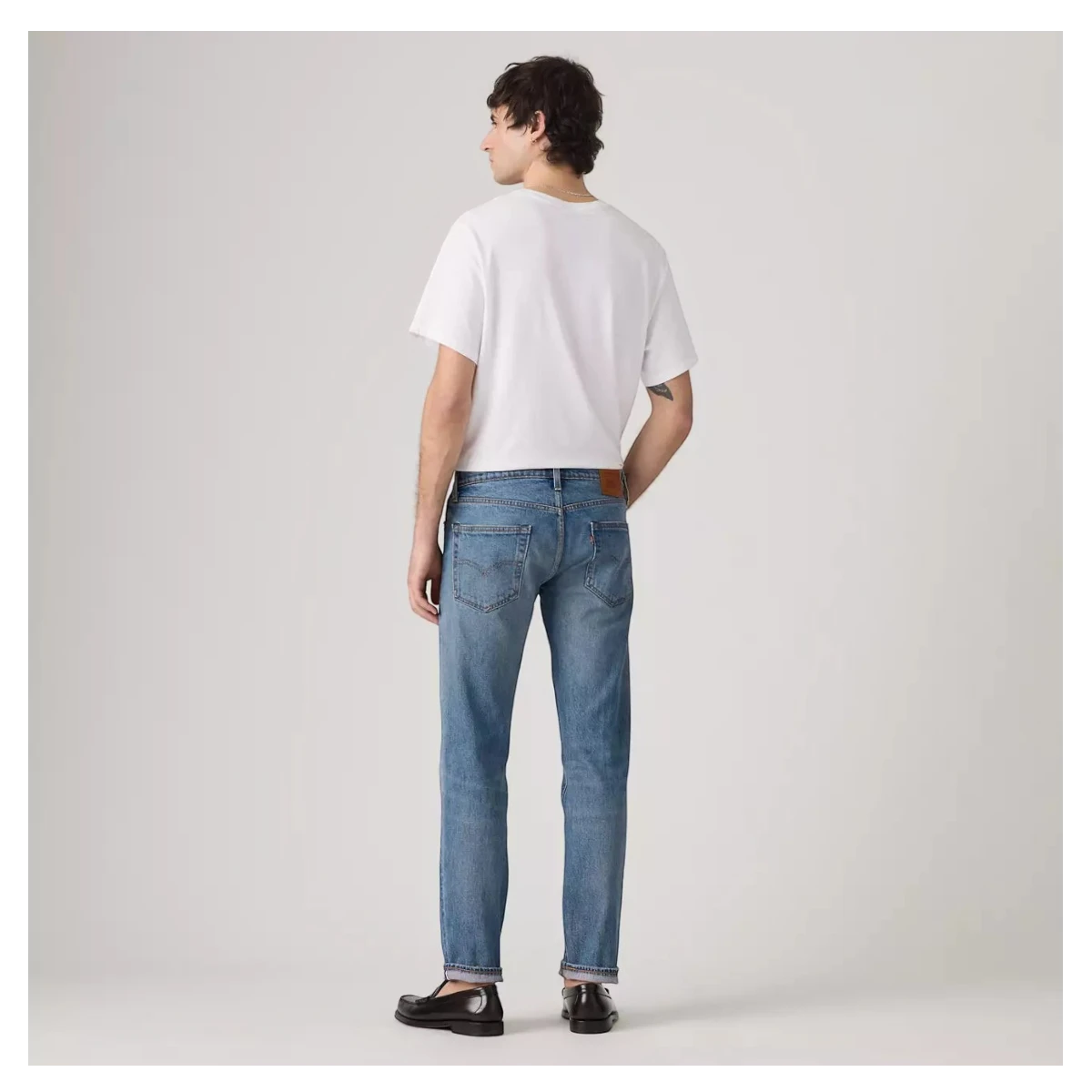 MILWORKS model wearing Levi's 502 Taper medium wash selvedge denim jeans from a back view
