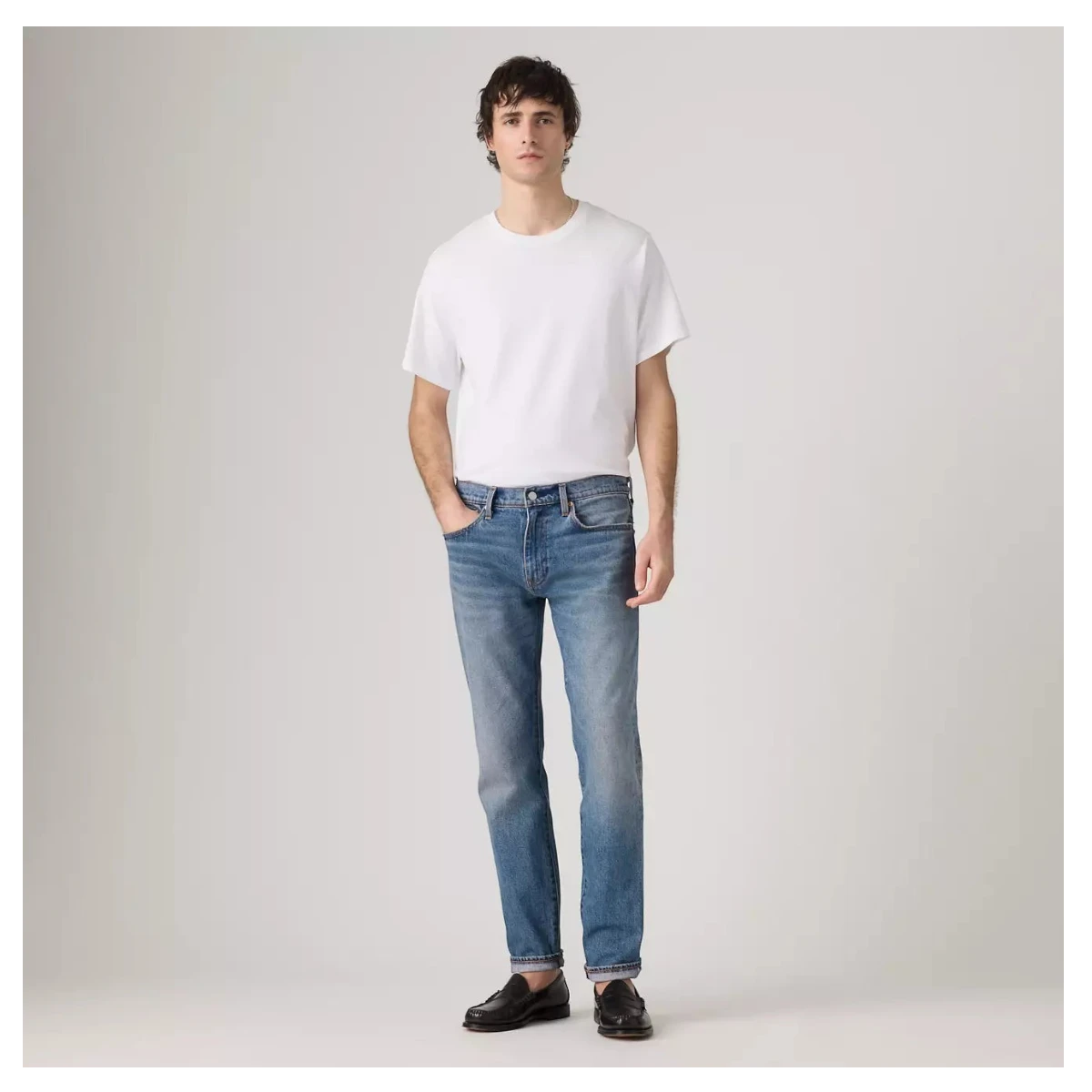 MILWORKS model wearing Levi's 502 Taper medium wash selvedge denim jeans with a white t-shirt and black loafers.
