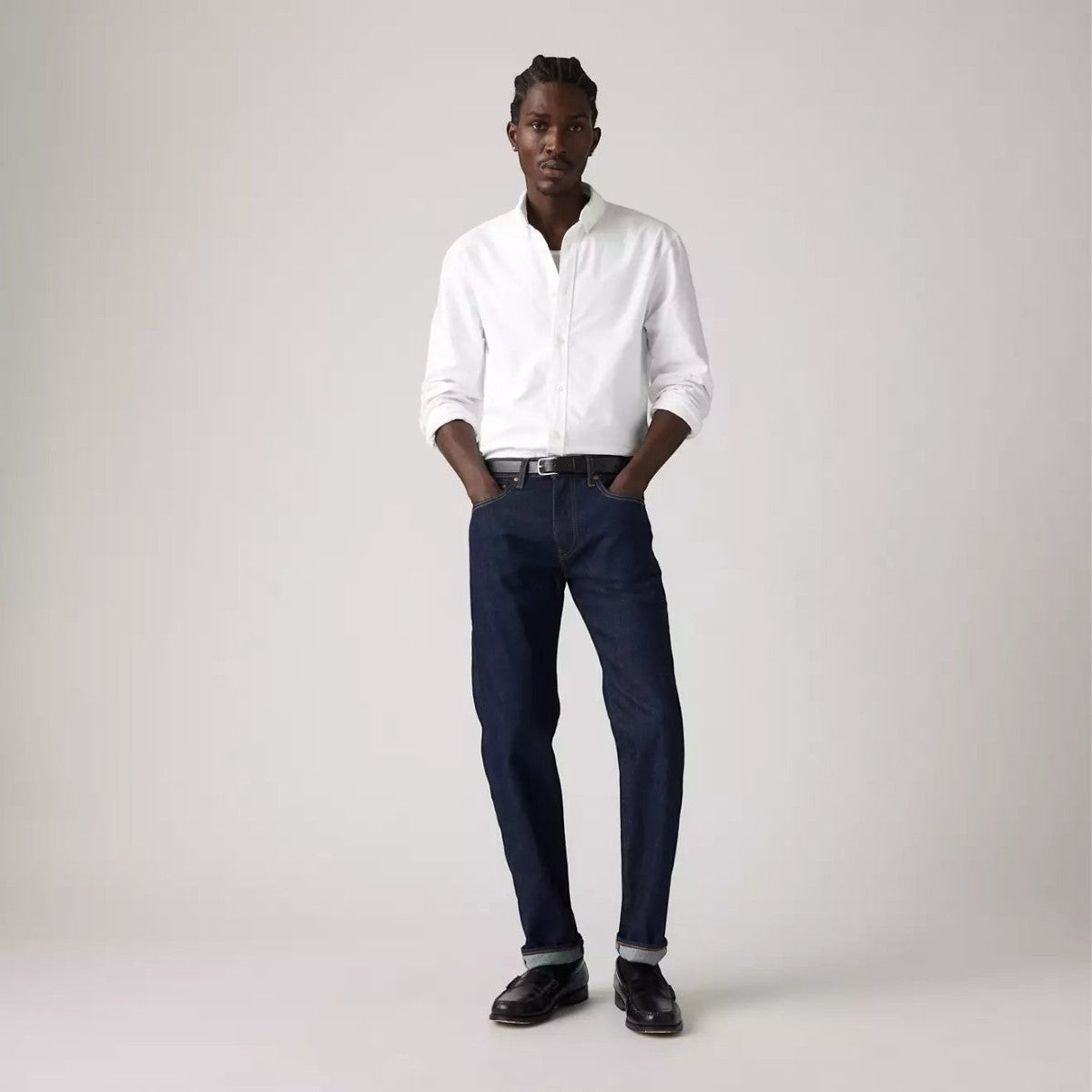 A model wearing MILWORKS Levi's 502 taper fit selvedge jeans in a dark wash with a white button-down shirt.
