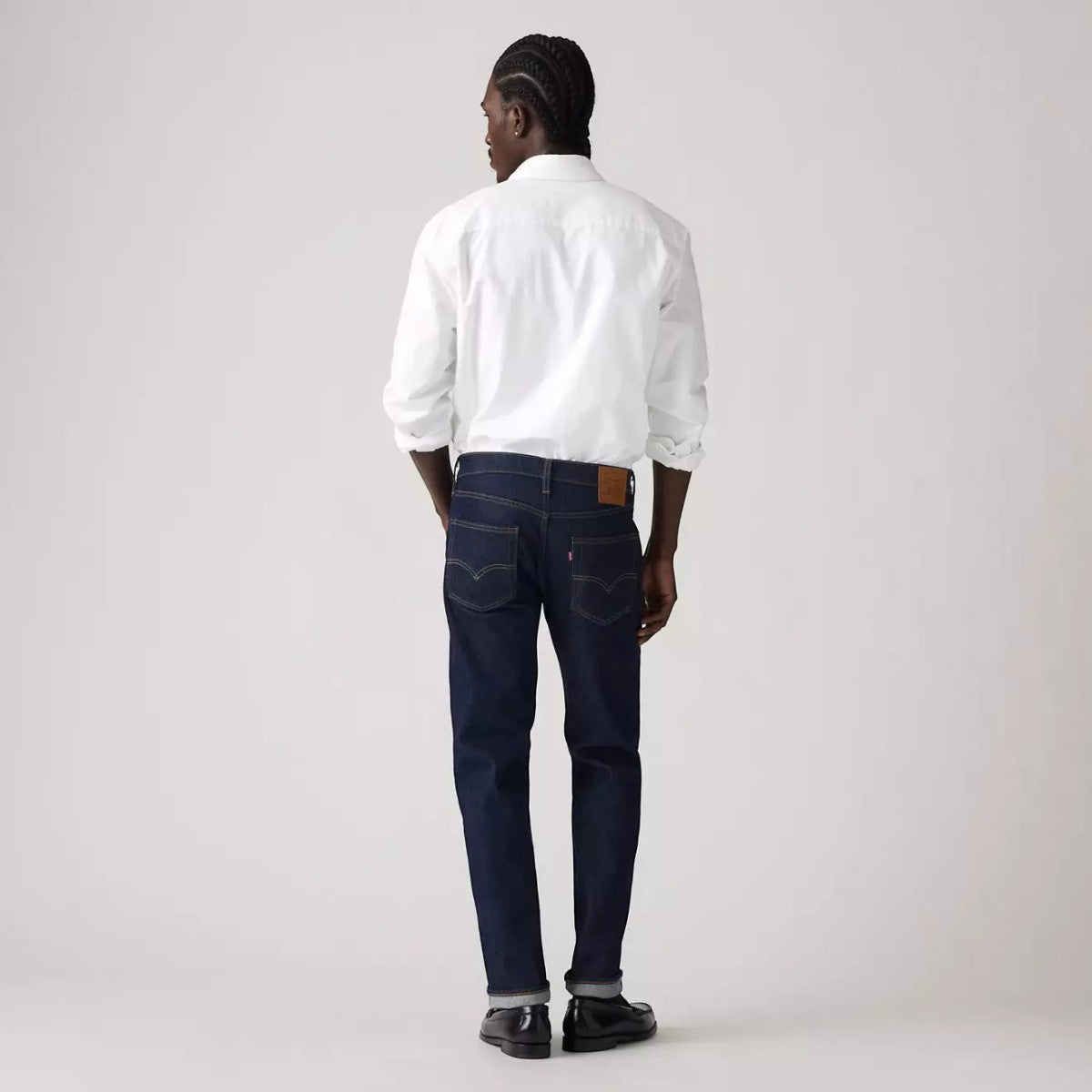 MILWORKS model wearing Levi's 502 Taper Fit dark wash selvedge denim jeans from the back with a white shirt