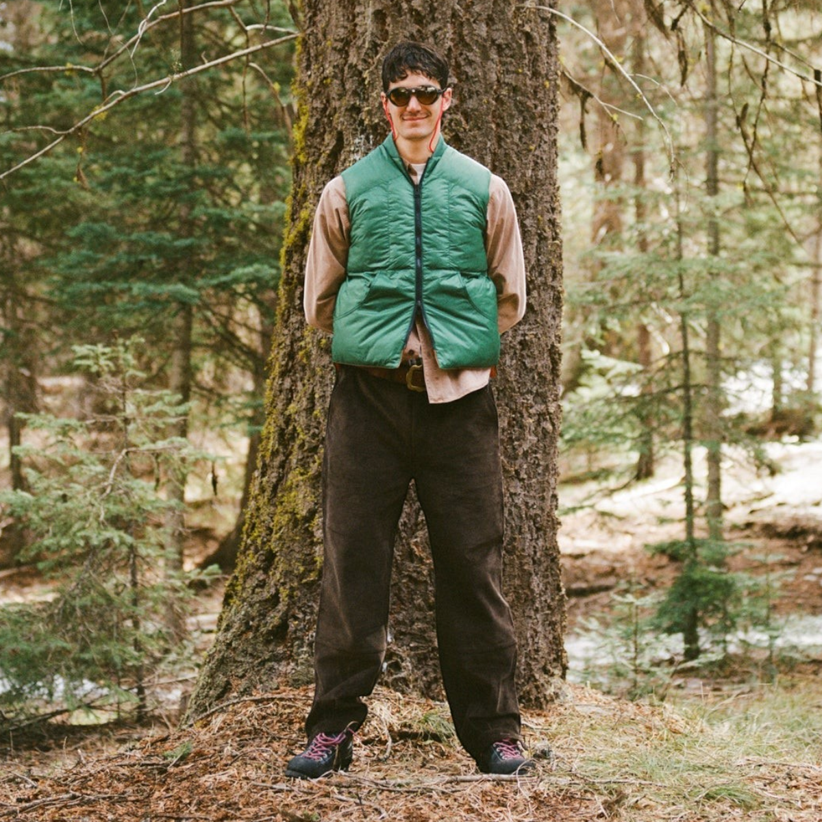 MILWORKS Minarets reversible nylon vest in pickle green worn by a man standing in a forest setting.