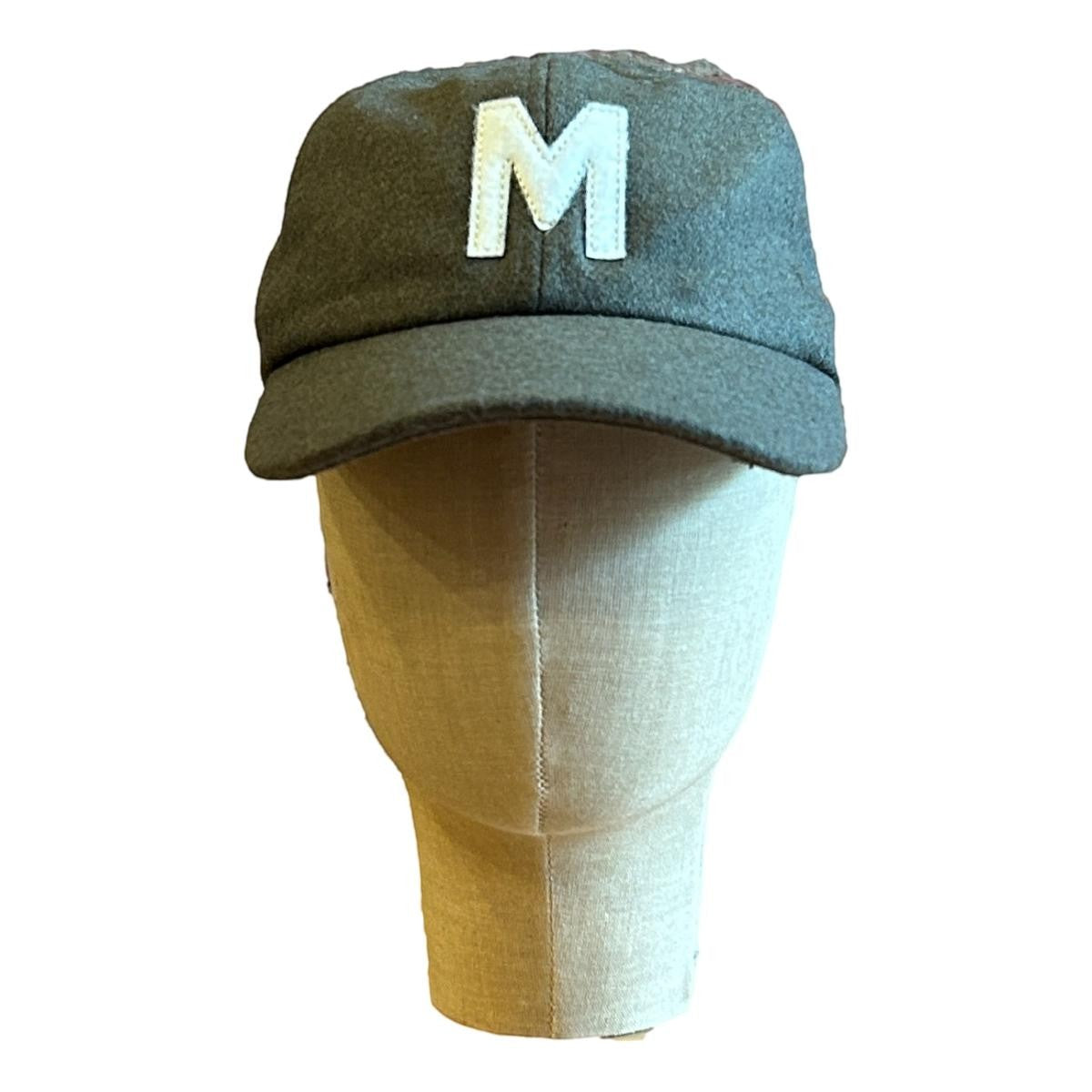 MILWORKS olive green wool blend unstructured cap with a white felt "M" logo, flat peak, and adjustable metal clasp.
