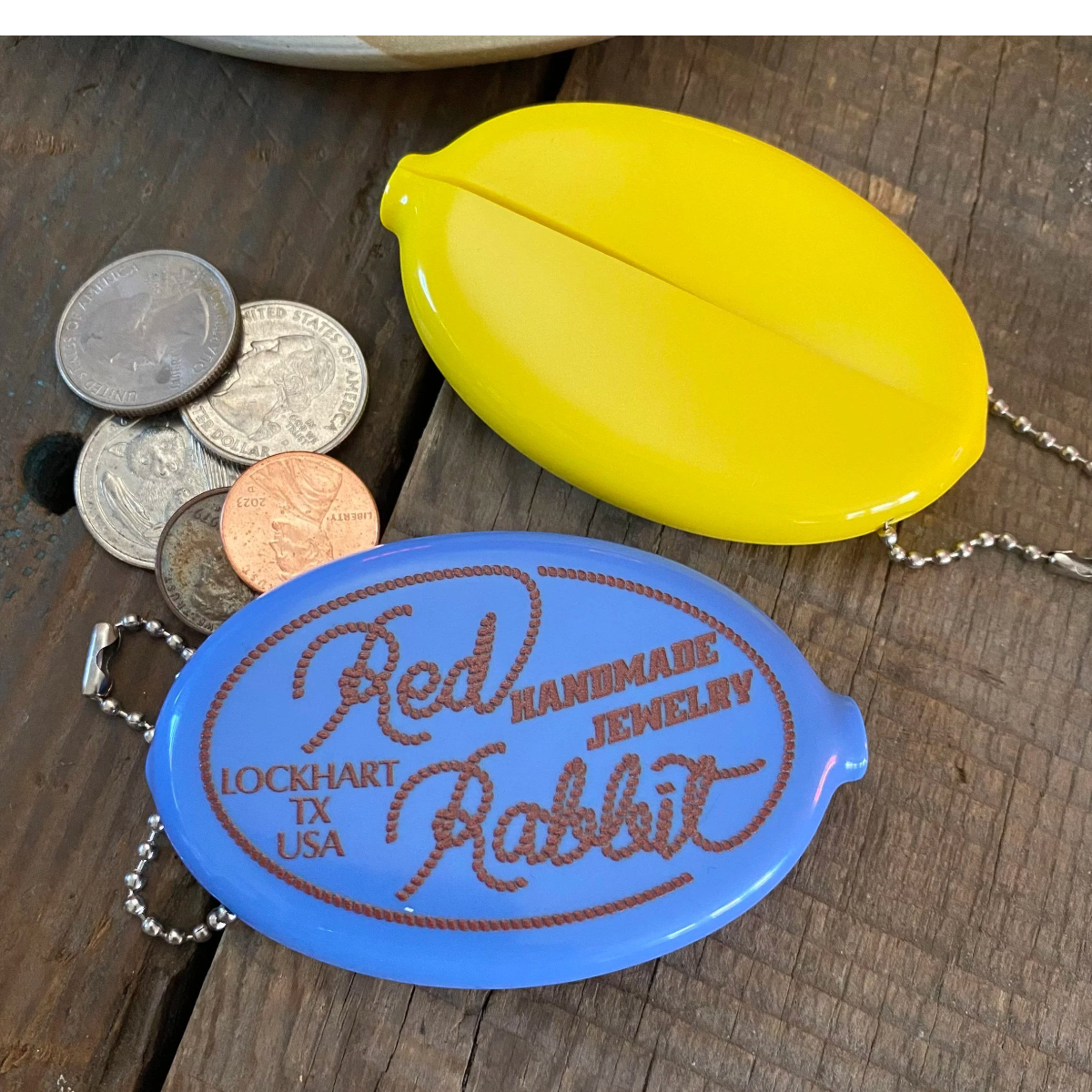 MILWORKS RR Coin Keeper squeeze pouches in steel blue and bright yellow with Red Rabbit rope logo on wooden surface