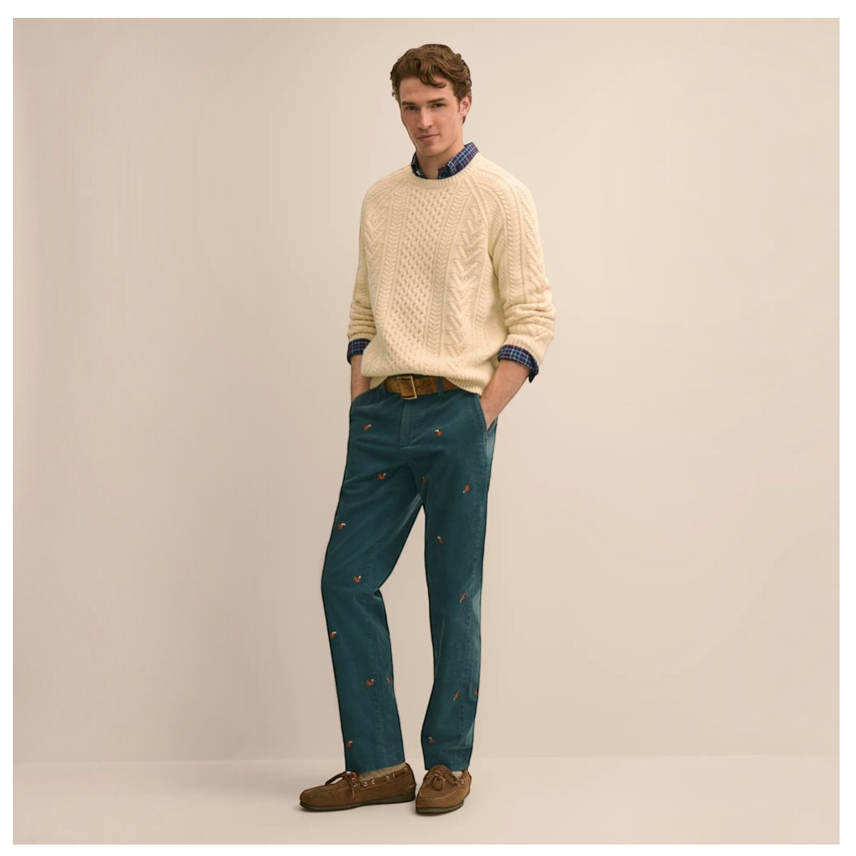 MILWORKS model wearing teal cotton corduroy pants with squirrel embroidery, cream cable knit sweater, and brown shoes.