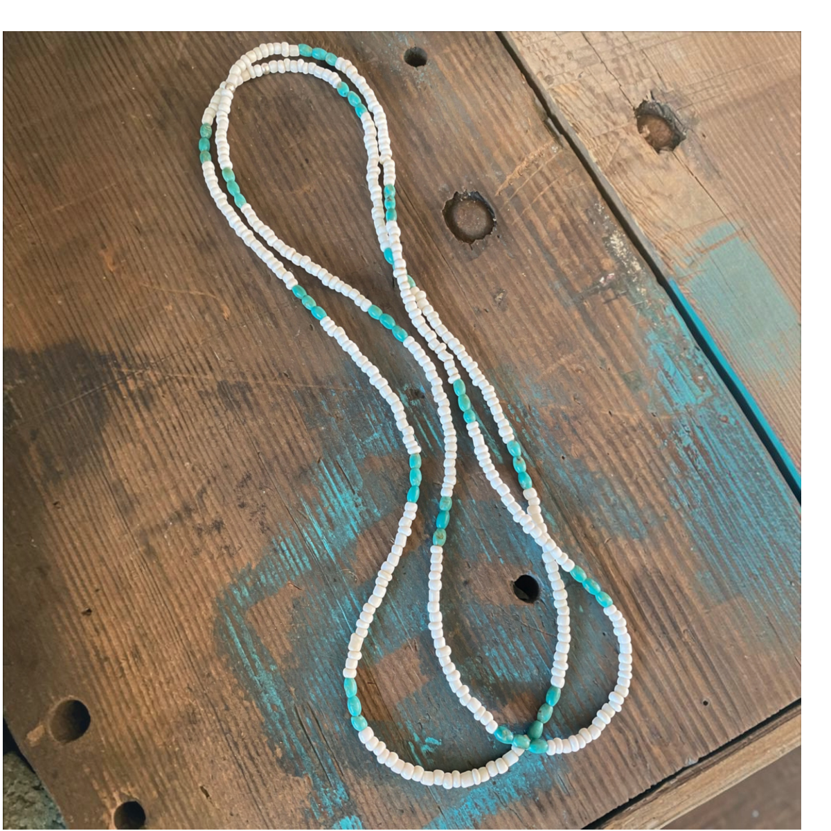MILWORKS 26-inch necklace featuring turquoise and white glass seed beads on a rustic wooden surface.