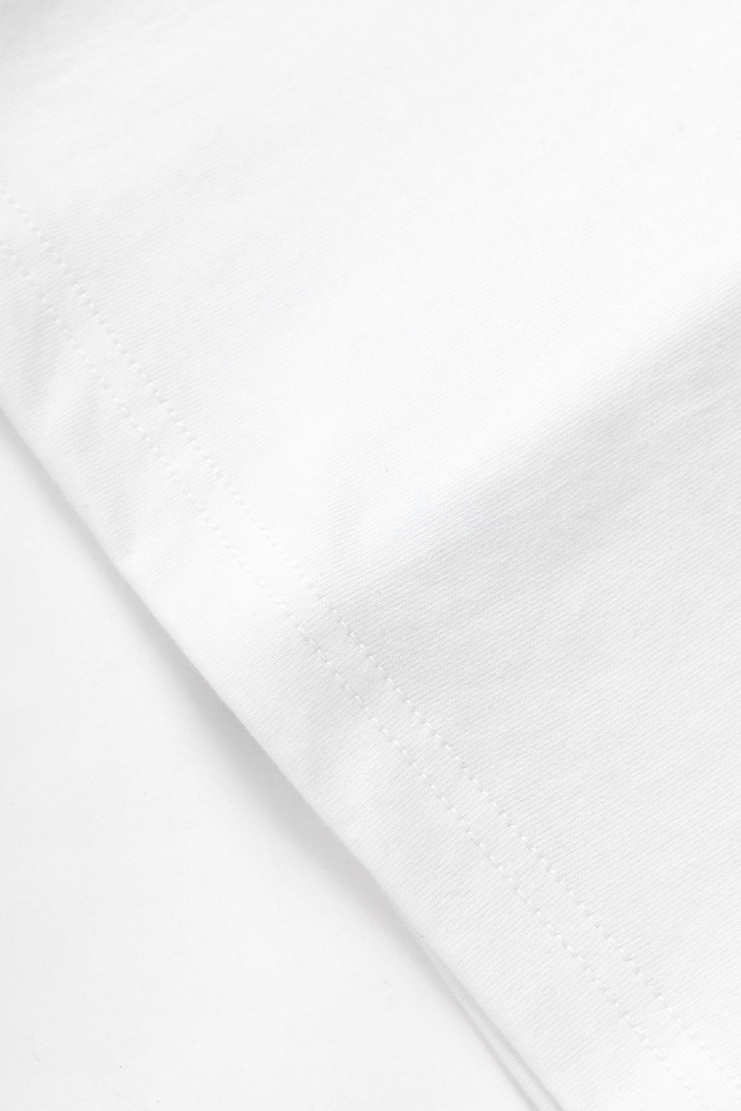 Close-up of the white organic cotton fabric and hem stitching on a MILWORKS 7.5oz Archive Tee.