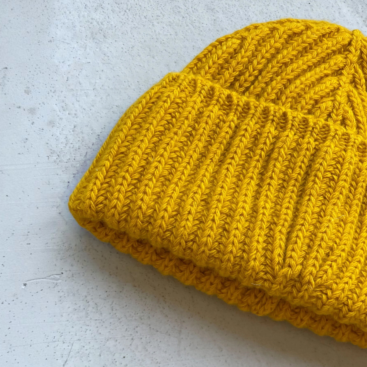 milworks.momusteau watch cap in old gold lambswool with a ribbed knit texture and folded cuff design.
